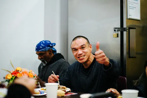 A man enjoying his Thanksgiving meal, giving a thumbs up. 